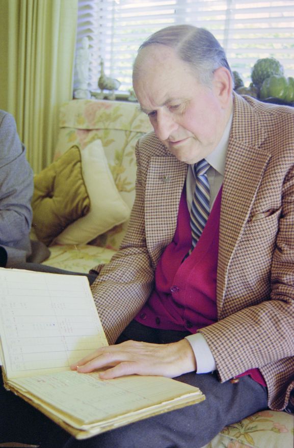 Portrait of Air Vice Marshal (retired) CL Siegert looking at his log book.