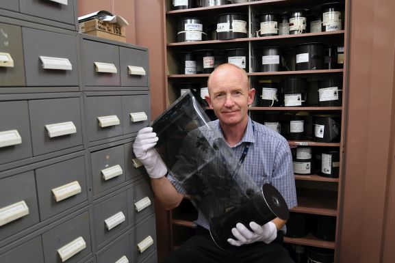 Air Force museum of New Zealand Keeper of Photographs, Matthew O'Sullivan, looking at a roll of aerial film in the Photo Archive.