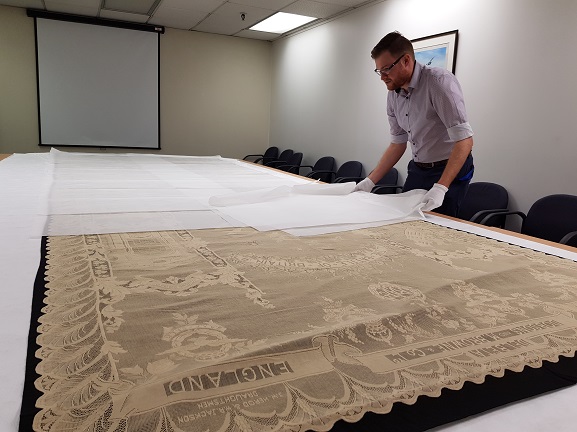 Collections Technician Jason Sim carefully preparing to put the Battle of Britain lace panel back into storage at the Air Force Museum of New Zealand.