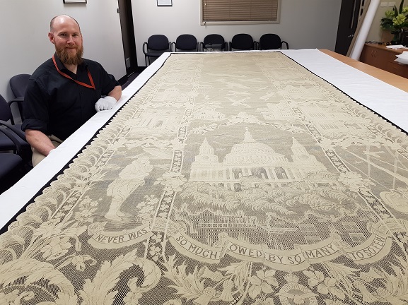Collections Technician Murray McGuigan with the Battle of Britain Lace Panel in the collection of the Air Force Museum of New Zealand.