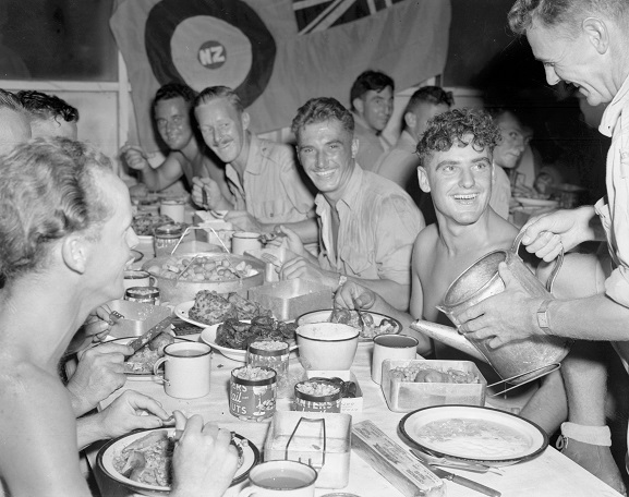 Group of airmen receiving Christmas dinner, served by officers, as is traditional at Christmas time.  Bougainville, 1944. Image ref PR4676, RNZAF Official.