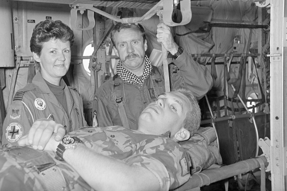 Corporal John Felton acts as patient on a stretcher in a No. 40 Squadron Hercules fitted out for aeromedical evacuation, with Squadron Leader Pauline Gwyther (No. 4626 Aeromedical Squadron, RAF) and Air Loadmaster Gary Porteous. Believed to be at Riyadh, Saudi Arabia, Feb-Mar 1991. Image ref PD12-28-91, RNZAF Official.