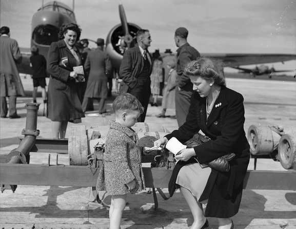 Mother and child beside a bomb trolley during an open day at RNZAF Station, Whenuapai, 1944. Image ref PR4088, RNZAF Official.